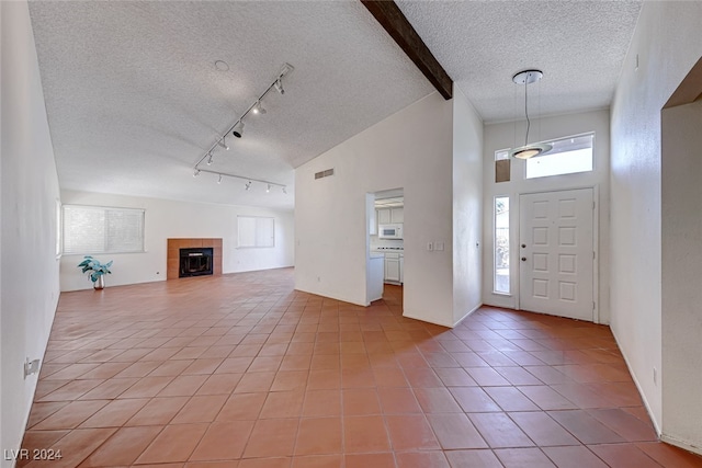 tiled entrance foyer with a fireplace, beam ceiling, a textured ceiling, and high vaulted ceiling