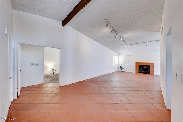 unfurnished living room with lofted ceiling with beams, a textured ceiling, a tile fireplace, and light tile patterned floors