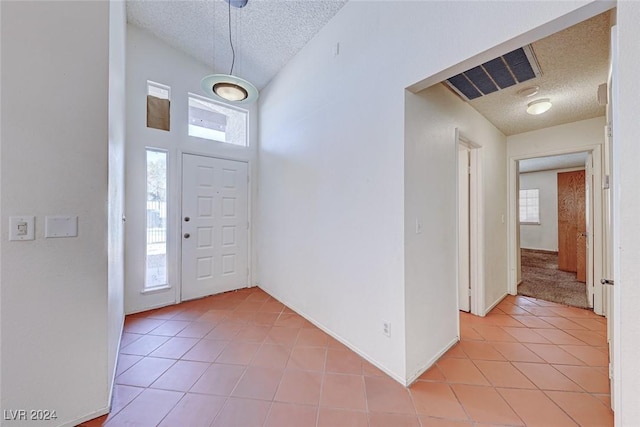 foyer entrance with light tile patterned floors, baseboards, visible vents, and a textured ceiling