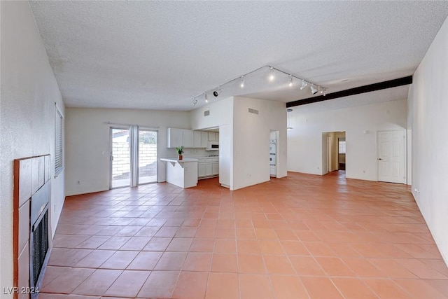 unfurnished living room featuring light tile patterned floors, a textured ceiling, rail lighting, and a fireplace