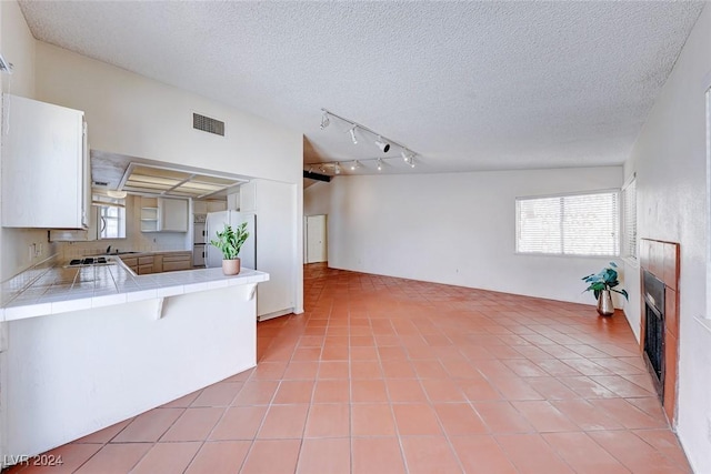 kitchen featuring tile countertops, light tile patterned floors, visible vents, and freestanding refrigerator