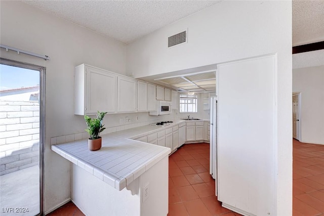 kitchen with visible vents, a sink, white cabinetry, and tile counters