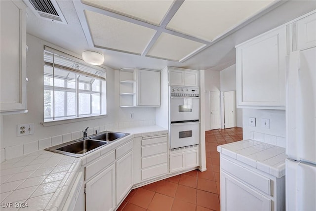 kitchen with visible vents, tile countertops, white appliances, and a sink