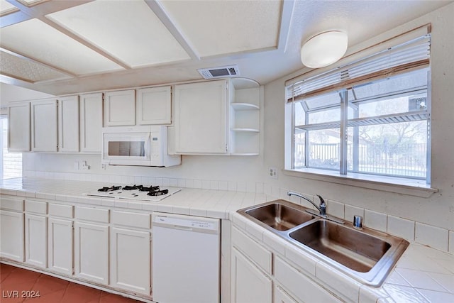 kitchen with visible vents, white appliances, white cabinetry, and a sink