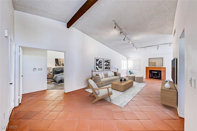 living area featuring light tile patterned flooring, beam ceiling, a fireplace, and a textured ceiling