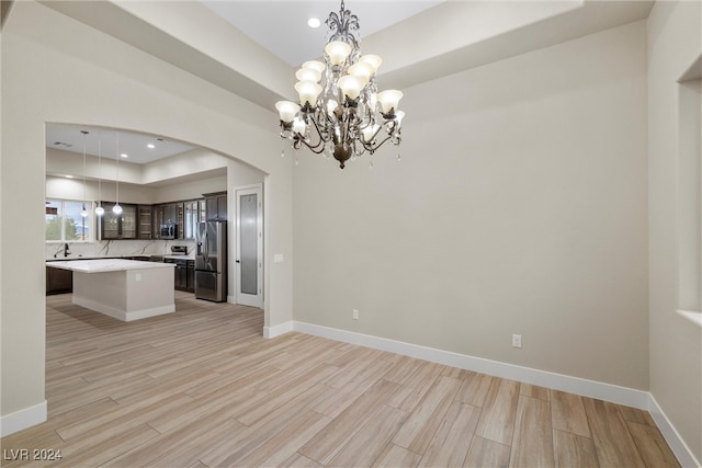 kitchen featuring a center island, hanging light fixtures, light wood-type flooring, appliances with stainless steel finishes, and a notable chandelier