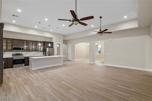 kitchen with a kitchen island, stainless steel appliances, decorative light fixtures, and light hardwood / wood-style floors