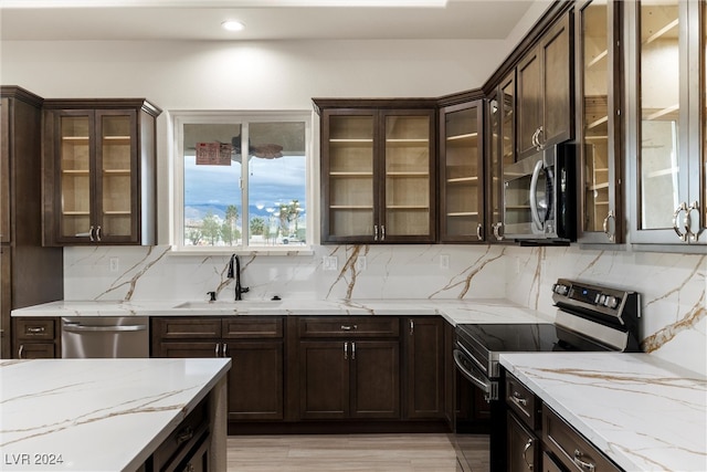 kitchen featuring backsplash, stainless steel appliances, light stone counters, and sink