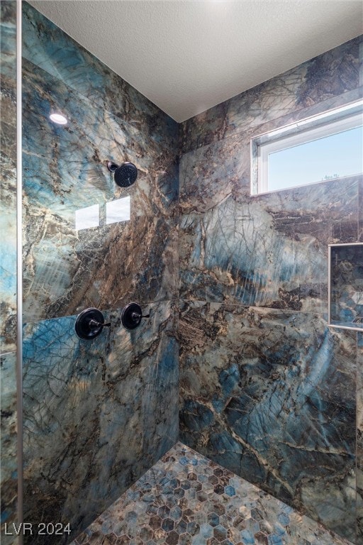 bathroom with a tile shower and a textured ceiling