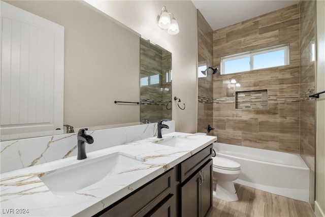 full bathroom with hardwood / wood-style floors, vanity, tiled shower / bath combo, and toilet