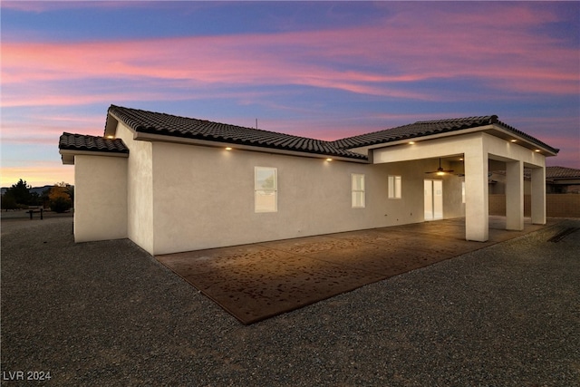 back house at dusk featuring a patio