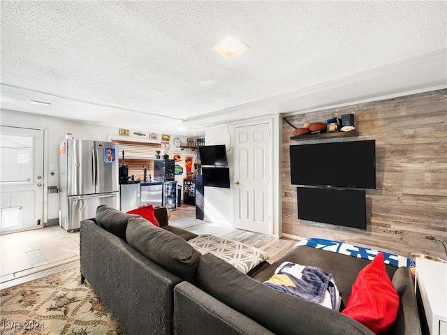 living room with wood walls, light hardwood / wood-style floors, and a textured ceiling