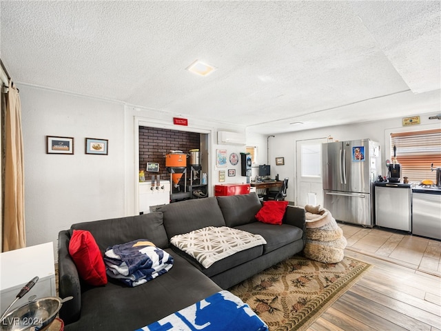 living room with a wall mounted air conditioner, a textured ceiling, and light hardwood / wood-style floors