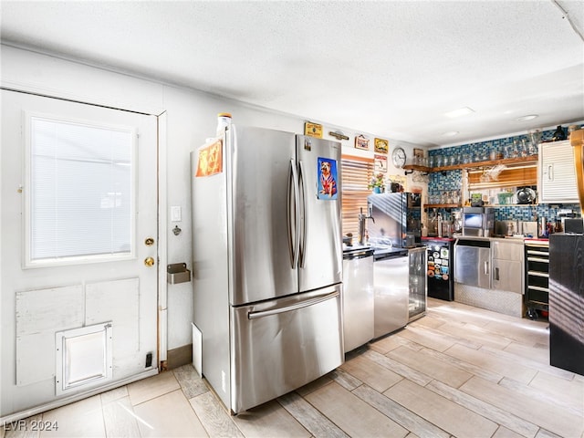 kitchen featuring stainless steel appliances, a textured ceiling, and light wood-type flooring