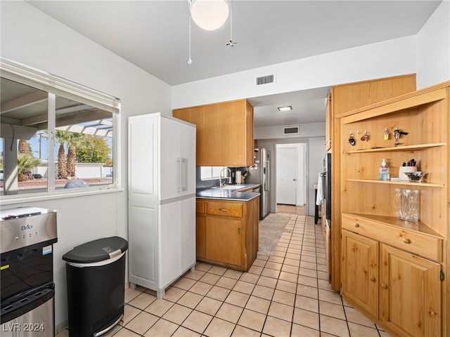 kitchen with light tile patterned floors, stainless steel fridge with ice dispenser, and sink