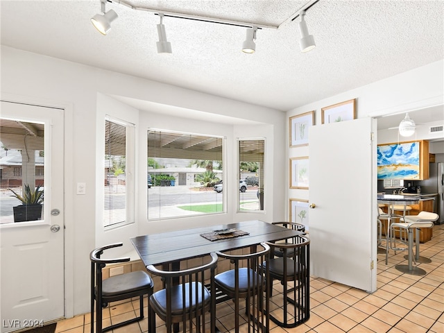 tiled dining area with rail lighting and a textured ceiling