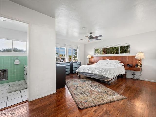 bedroom with multiple windows, ceiling fan, dark hardwood / wood-style flooring, and heating unit