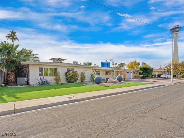 ranch-style home featuring a front yard, a garage, and central air condition unit