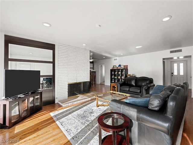 living room with hardwood / wood-style floors and a brick fireplace