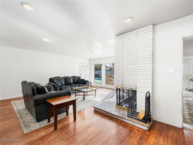 living room with hardwood / wood-style floors and a brick fireplace