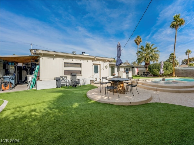 back of house featuring a lawn, an outbuilding, and a patio