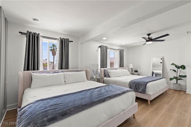 bedroom with ceiling fan, light hardwood / wood-style flooring, and a textured ceiling