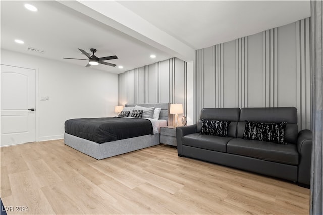 bedroom featuring ceiling fan, light hardwood / wood-style flooring, and beamed ceiling