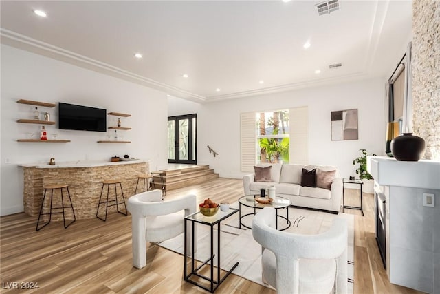 living room featuring ornamental molding, light hardwood / wood-style floors, and bar area