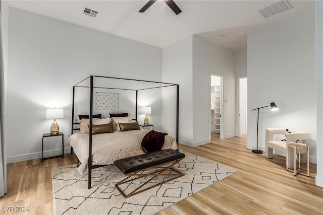 bedroom with ceiling fan, light hardwood / wood-style floors, and a spacious closet