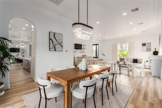 dining area with an inviting chandelier, ornamental molding, and light hardwood / wood-style flooring