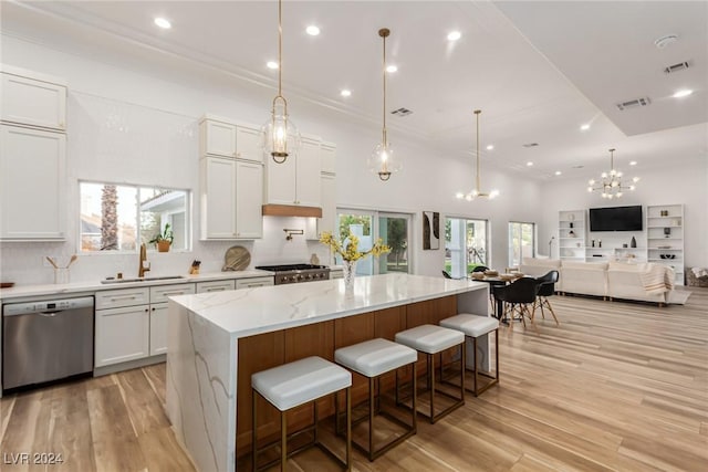 kitchen with stainless steel dishwasher, a kitchen island, white cabinetry, and sink