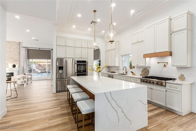 kitchen with a kitchen island, white cabinets, appliances with stainless steel finishes, and light hardwood / wood-style flooring