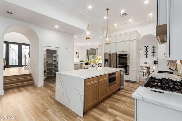 kitchen with light stone countertops, stainless steel appliances, a spacious island, white cabinetry, and sink