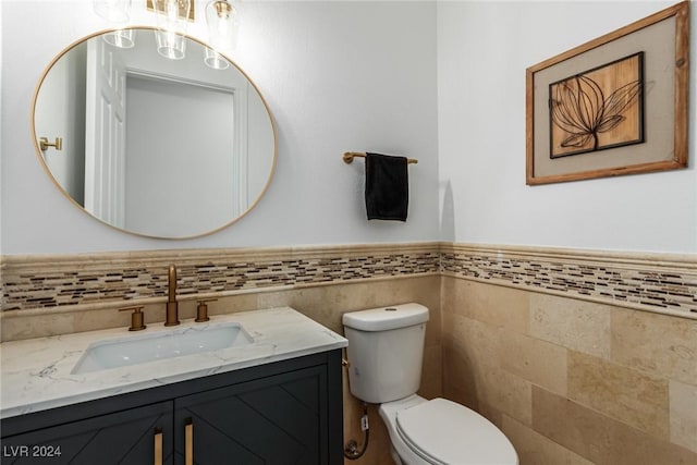 bathroom with tile walls, vanity, and toilet