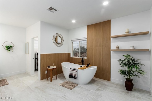 bathroom with a washtub and wooden walls