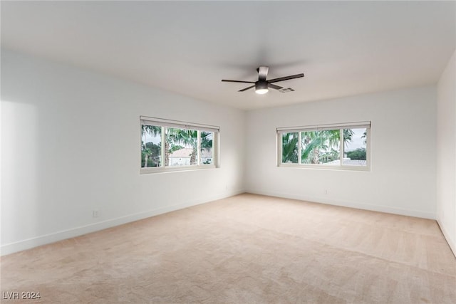 carpeted empty room featuring ceiling fan and a wealth of natural light