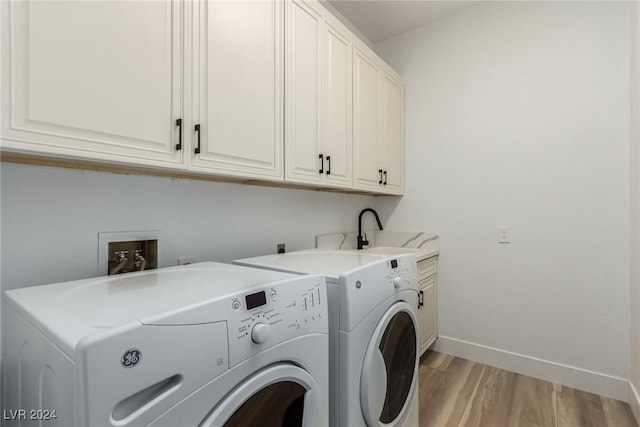 laundry area featuring sink, light hardwood / wood-style floors, cabinets, and independent washer and dryer