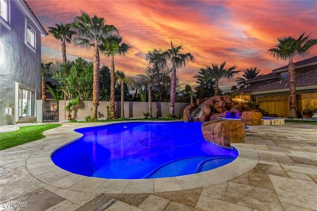 pool at dusk with a patio area