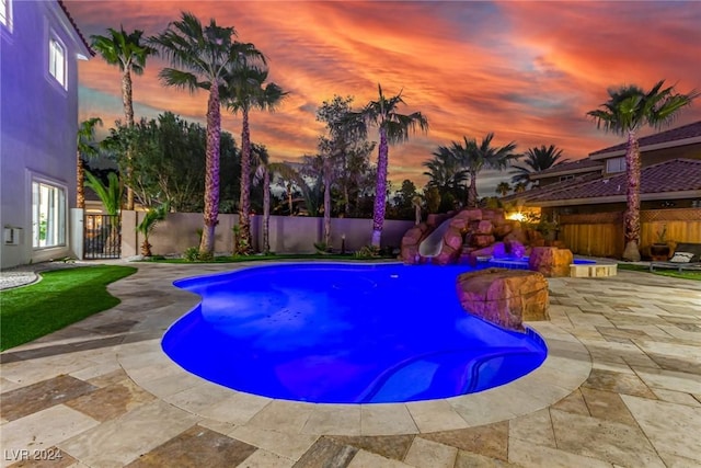 pool at dusk featuring a patio