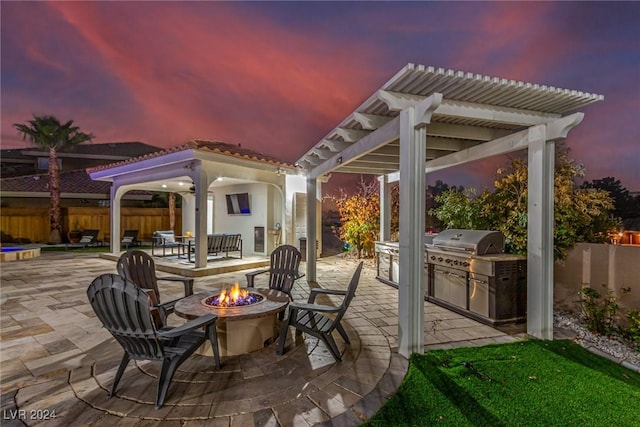 patio terrace at dusk with a fire pit, a grill, and area for grilling