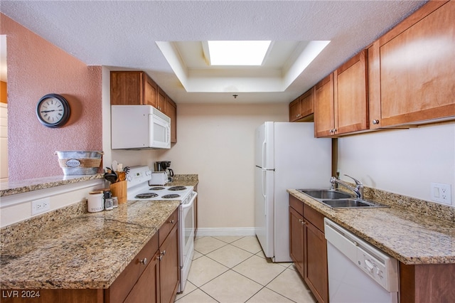 kitchen featuring sink, white appliances, light tile patterned floors, a textured ceiling, and a raised ceiling