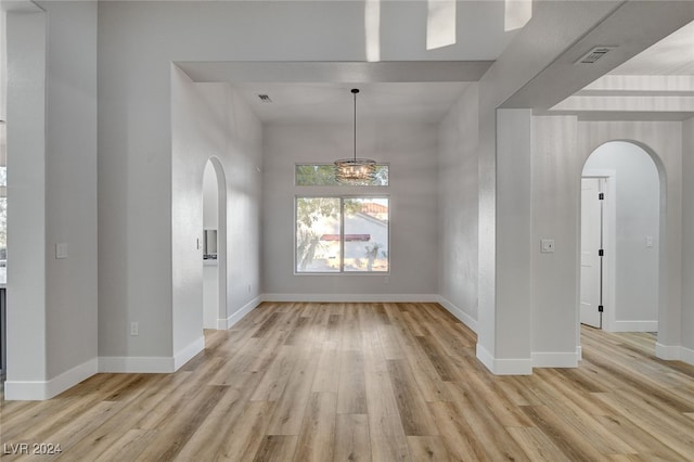 unfurnished room featuring light hardwood / wood-style flooring and a chandelier