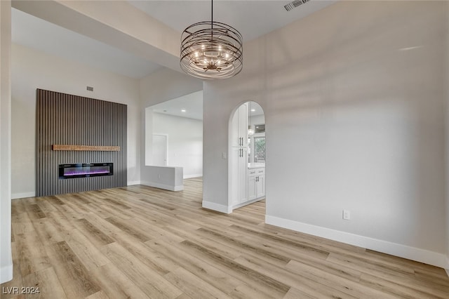 unfurnished living room with a notable chandelier and light wood-type flooring