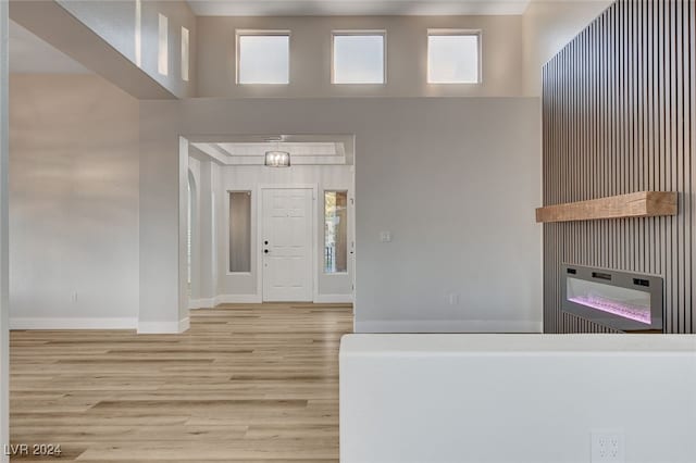 foyer featuring a towering ceiling, light hardwood / wood-style floors, and plenty of natural light