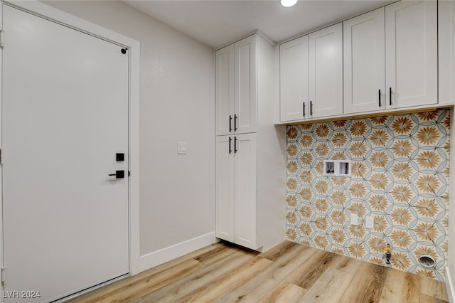 clothes washing area featuring cabinets and light wood-type flooring