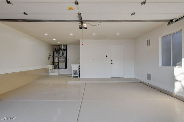 garage with strapped water heater and a garage door opener