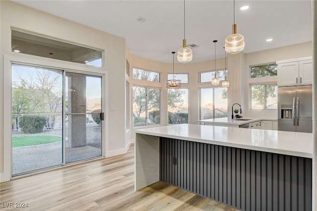 kitchen featuring white cabinets, light hardwood / wood-style floors, a wealth of natural light, and built in refrigerator