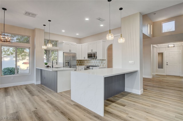 kitchen with kitchen peninsula, white cabinetry, hanging light fixtures, and appliances with stainless steel finishes