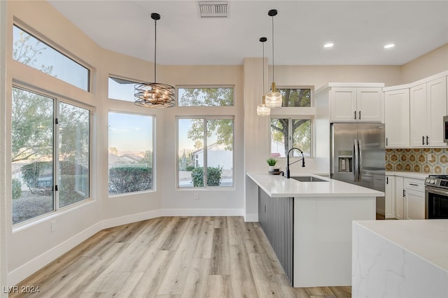 kitchen with white cabinets, sink, light wood-type flooring, appliances with stainless steel finishes, and a notable chandelier