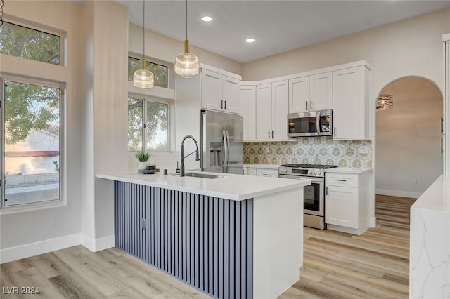 kitchen featuring white cabinets, a healthy amount of sunlight, kitchen peninsula, and appliances with stainless steel finishes